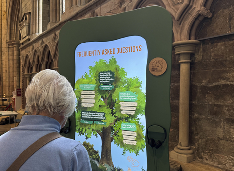 A woman looking at the Frequently Asked Questions board at the Missing Lynx Exhibition